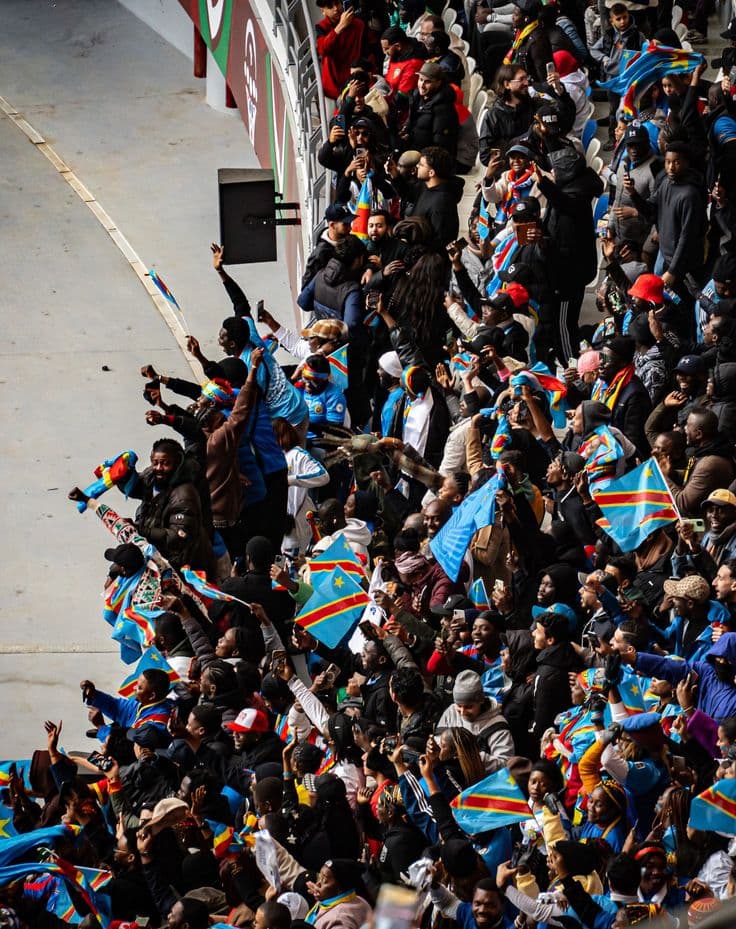 Foule dans un stade, drapeaux de la RDC et téléphones levés